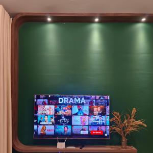 a flat screen tv sitting on a green wall at One Bedroom Troika Kota Bharu by AGhome in Kota Bharu