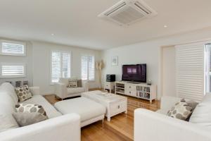 sala de estar con muebles blancos y TV de pantalla plana en The Hamptons, en Cowes