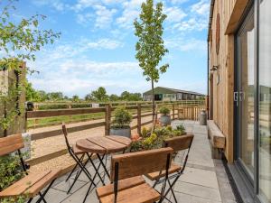 a patio with a table and chairs and a tree at The Old Haybarn in Longford