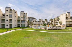 a large grassy yard in front of two apartment buildings at Ocean Breeze Retreat 2bed 2bath, Heated Pool! in South Padre Island