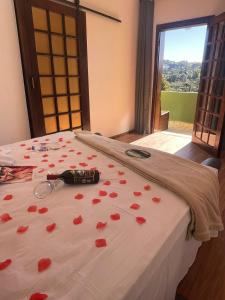 a bed with red rose petals on it at Pousada Casa de Campos Mountain House in Campos do Jordão