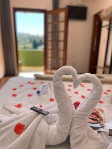 two towels shaped like swans laying on a bed at Pousada Casa de Campos Mountain House in Campos do Jordão