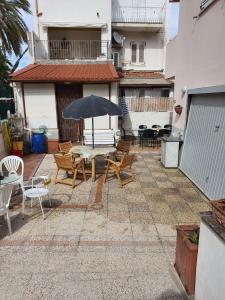 a patio with a table and chairs and an umbrella at Case Vacanza Armando "Lipari" in Canneto