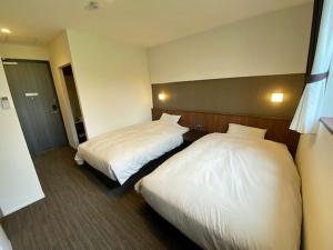 duas camas num quarto de hotel com lençóis brancos em Crest Asago em Asago