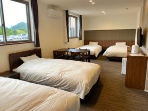 um quarto de hotel com duas camas e uma mesa em Crest Asago em Asago