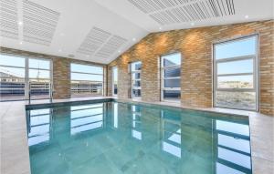 an empty swimming pool in a building with windows at Amazing Home In Hvide Sande With Outdoor Swimming Pool in Hvide Sande