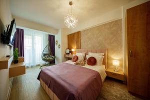 a bedroom with a bed and a chandelier at Royale Sundance 305 Infinity Beach Pool & Spa Mamaia Nord in Mamaia Nord