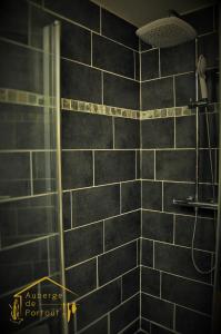 a bathroom with a shower with black tiles at Auberge de Portout in Chanaz