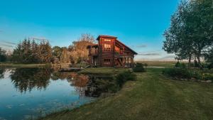 une maison en bois installée à côté d'un lac dans l'établissement Laukupės sodyba, à Rokiškis