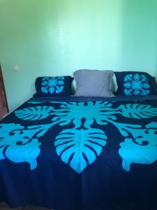a bed with a blue bedspread with a tiger design on it at Maison soleil in Vaihi