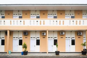 un bâtiment avec des portes blanches et des plantes en pot dans l'établissement RedDoorz at Putri Syariah Brebes, 