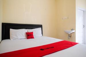 uma cama com um cobertor vermelho em cima em RedDoorz at Putri Syariah Brebes 