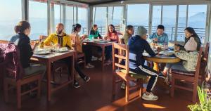 un gruppo di persone seduti ai tavoli in un ristorante di Hotel High Ground Inn Sarangkot a Pokhara