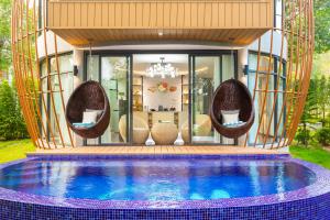a house with a swimming pool with chairs around it at Bird Nest Villas by Mafiya in Sihanoukville