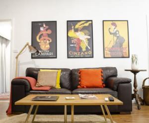 uma sala de estar com um sofá de couro preto e cartazes em Mary Lemon Cottage - Heritage Home em Orange