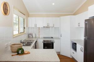 a kitchen with white cabinets and a counter top at Reflections Lennox Head - Holiday Park in Lennox Head