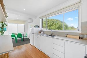 eine Küche mit weißen Schränken und einem großen Fenster in der Unterkunft Moody's Beach Apartment in Blairgowrie