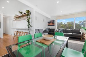 sala de estar con mesa de cristal y sillas verdes en Moody's Beach Apartment, en Blairgowrie