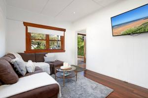 a living room with a couch and a flat screen tv at 2-bedroom Cottage in Redcliffe - 6A in Redcliffe