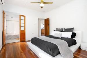 a white bedroom with a black bed and a ceiling fan at 2-bedroom Cottage in Redcliffe - 6A in Redcliffe