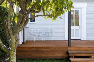 a porch with two chairs on a wooden deck at 2-bedroom Cottage in Redcliffe - 6A in Redcliffe