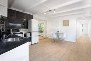 een keuken met witte apparatuur en een tafel met stoelen bij 2-Bedroom Holiday rental in Redcliffe in Redcliffe