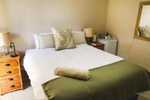 a bedroom with a large white bed and a wooden dresser at Serendipity Boutique Guest house in Welkom