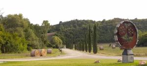 a large sculpture in the grass next to a road at Hotel Antica Tabaccaia Resort in Terranuova Bracciolini