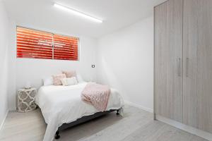 Habitación blanca con cama y ventana en Waterfront two-bedroom Getaway en Scarborough