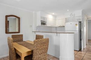 Una cocina con mesa y sillas y un refrigerador. en Villa Aqua Riverside Retreat with Pool, en Noosaville