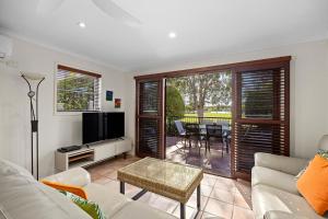 Una sala de estar con un sofá y un televisor. en Villa Aqua Riverside Retreat with Pool, en Noosaville