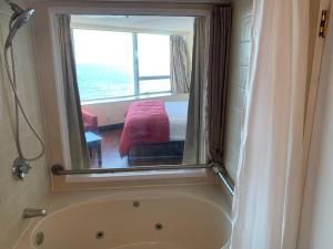 a bathroom with a tub and a bedroom with a window at Atlantic Palace Beachfront Ocean View in Atlantic City +7 photos