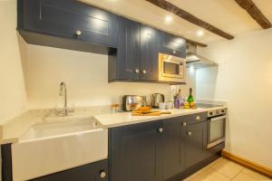 a kitchen with blue cabinets and a sink at Maes Madog Cottages in Betws-y-coed