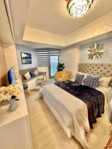 ein Schlafzimmer mit einem großen Bett und ein Wohnzimmer in der Unterkunft Aurum Bliss Suite at Azure North in Lagundi