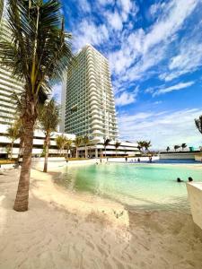 una playa con palmeras y un gran edificio en Aurum Bliss Suite at Azure North, en Lagundi