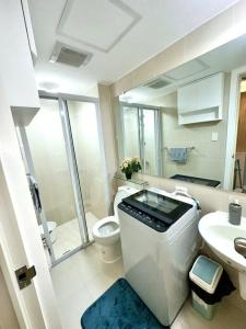 Baño blanco con aseo y lavamanos en Aurum Bliss Suite at Azure North, en Lagundi