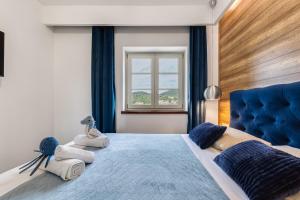 una camera da letto con letto blu, asciugamani e finestra di TEONA Luxury Apartment with terrace a Sali (Sale)