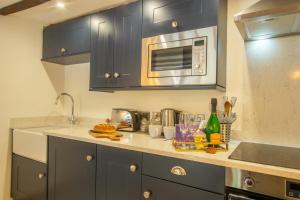 cocina con armarios azules y microondas en Maes Madog Cottages en Betws-y-coed