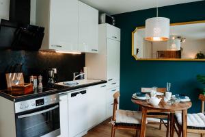 une cuisine avec des placards blancs et une petite table dans l'établissement Design Home Office & Central Hideaway - EAH, ZEISS, SCHOTT in 5 min, à Iéna