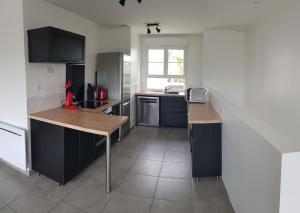 eine Küche mit schwarzen Schränken und einer hölzernen Arbeitsplatte in der Unterkunft La Patalisse, maison type 3 et jardin in Joue-les-Tours