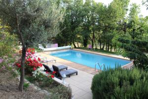 uma piscina num jardim com um banco e flores em Mas Auroma em Murs