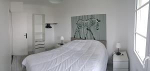 ein Schlafzimmer mit einem weißen Bett mit einem Pferd an der Wand in der Unterkunft La Patalisse, maison type 3 et jardin in Joue-les-Tours