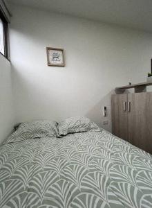 a bed with two pillows and a clock on the wall at Acogedor aparta/estudio al norte cc viva in Barranquilla