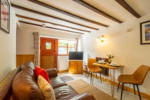 a living room with a leather couch and a table at Maes Madog Cottages in Betws-y-coed