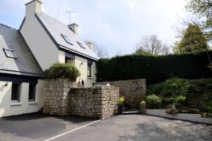 uma casa branca com uma parede de pedra ao lado de uma entrada em Chambres d'Hôtes Ailes et Iles em Pleudaniel