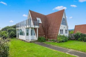 a house with a metal roof and a green yard at Alpha - Otaki Beach Holiday Home in Otaki Beach