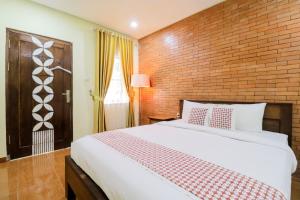 Un dormitorio con una cama grande y una pared de ladrillo. en Penginapan Widodo Syariah Borobudur, en Magelang
