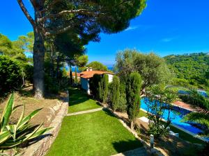a garden with a swimming pool and trees and a house at Villa Buda Begur in Begur