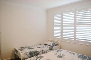 a bedroom with two beds and a window with blinds at Seaspray no 5 - Bring your own linen. in South West Rocks