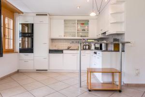 a kitchen with white cabinets and a table at Apartment Dolce Vita - GRIWA RENT AG in Grindelwald